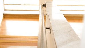 Una habitación con una cama, un ventanal con persianas y un cartel en la pared.