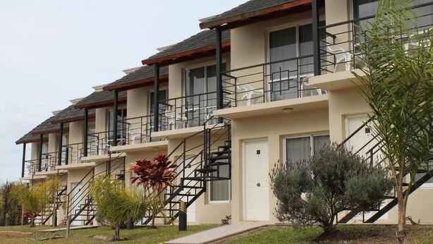 A multi-story residential building with balconies, staircases, and a well-maintained lawn. - Brisas del Lago Apartamentos (Colon)