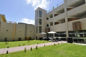 Um edifício moderno com vários andares, área de estar ao ar livre e um jardim bem cuidado.