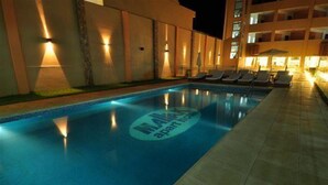 A swimming pool with lounge chairs and a building in the background. - Mallak Apart Hotel (Costa Azul)