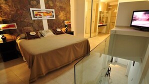 A hotel room with a bed, a television, and a bathroom visible through an open door. - Mallak Apart Hotel (Costa Azul)