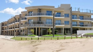 A multi-story hotel with balconies, a beach view, and a sandy foreground. - Mallak Apart Hotel (Costa Azul)