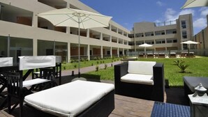 A modern outdoor seating area with tables and chairs, umbrellas, and a poolside lounge. - Mallak Apart Hotel (Costa Azul)