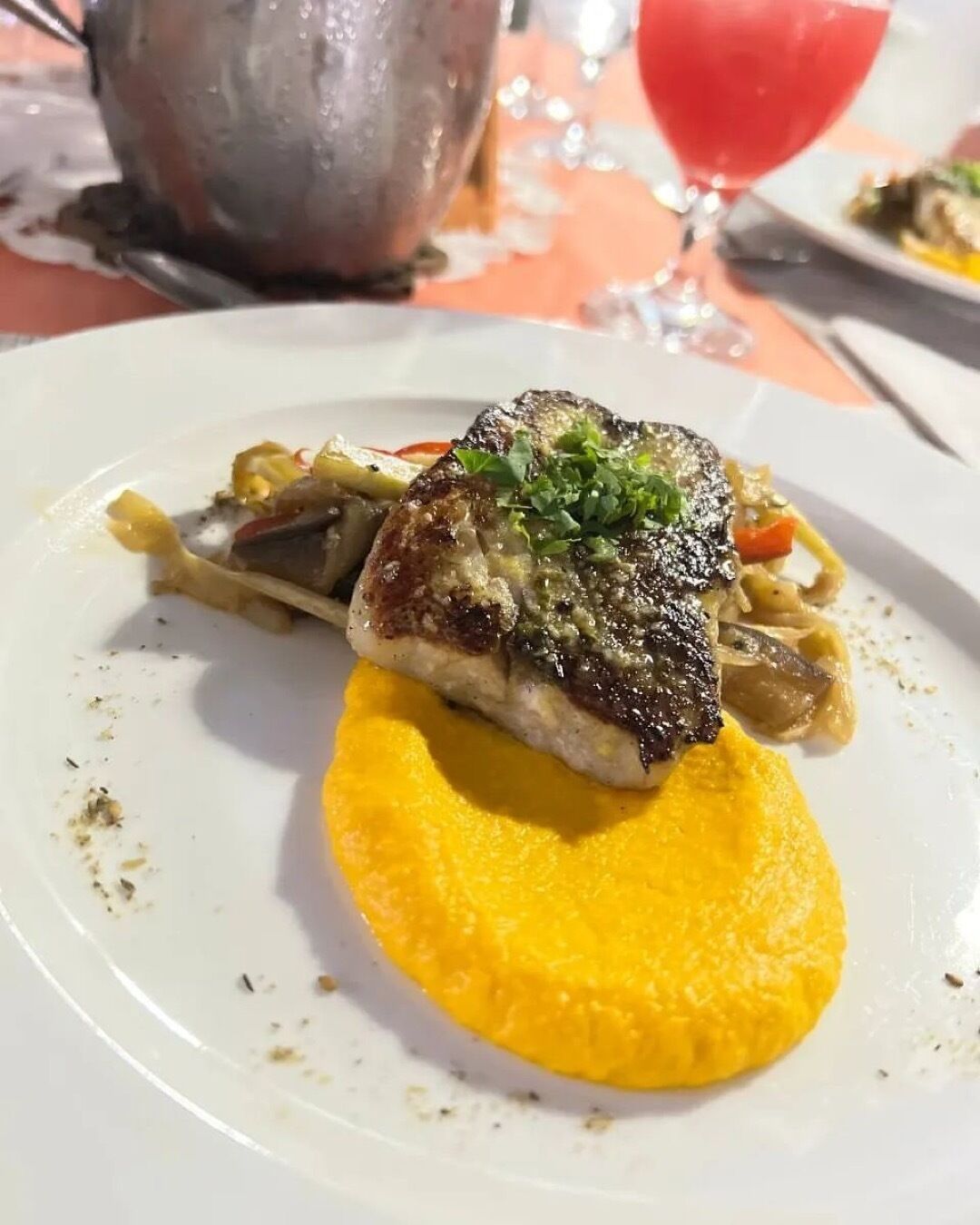 Un plato con un trozo de carne a la parrilla, verduras y un puré amarillo.