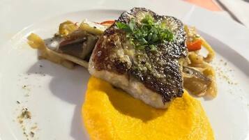 Un plato con un trozo de carne a la parrilla, verduras y un puré amarillo.