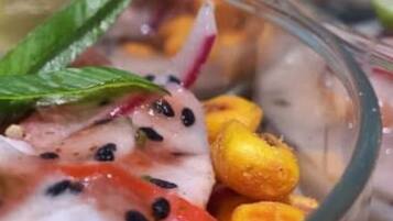 Une vue rapprochée d’un plat de fruits de mer composé de crevettes, de maïs et d’herbes aromatiques.