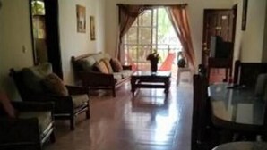 Ein Wohnzimmer mit einer Sofagarnitur, einem Couchtisch und einem Essbereich mit Tisch und Stühlen.