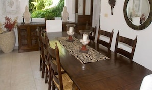 A dining area with a wooden table, chairs, and a zebra-patterned runner. There are decorative vases on the table and a large mirror on the wall. - Villa Florencia (Punta Cana)