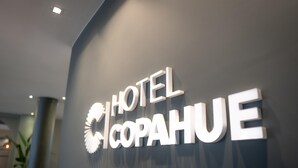 Een hotelschilt met de naam 'HOTEL COPAHUE' in grote, witte letters op een donkere achtergrond.