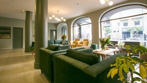 Een moderne lobby met groene banken, gele stoelen en grote ramen.