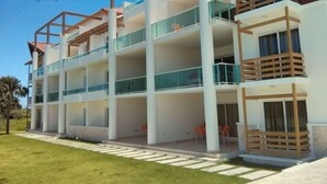 A multi-story hotel with balconies, outdoor seating, and a well-maintained lawn.