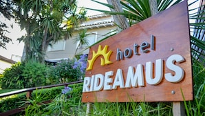 A wooden sign with the text "hotel RIDEAMUS" and a crown symbol. - Hotel Rideamus (Villa Gesell)