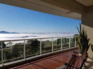 A balcony with a wooden floor, a bench, and a potted plant. - Hotel Kleinsberg (Bom Principio)