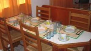 A dining area with a wooden table set for four, surrounded by chairs. - Green Hill Saliña Inn (Curaçao)