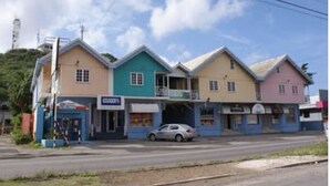 A row of colorful buildings with a car parked in front. - Green Hill Saliña Inn (Curaçao)