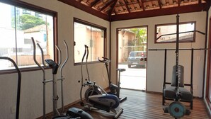 Academia com equipamentos de ginástica, incluindo esteiras, bicicletas ergométricas e um banco de musculação.