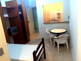 A small room with a bed, a TV, a table with chairs, and a mirror.
