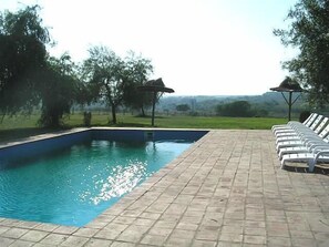 A rectangular swimming pool with a tiled deck and lounge chairs on one side. - Cabañas The Bakers (San Pedro)