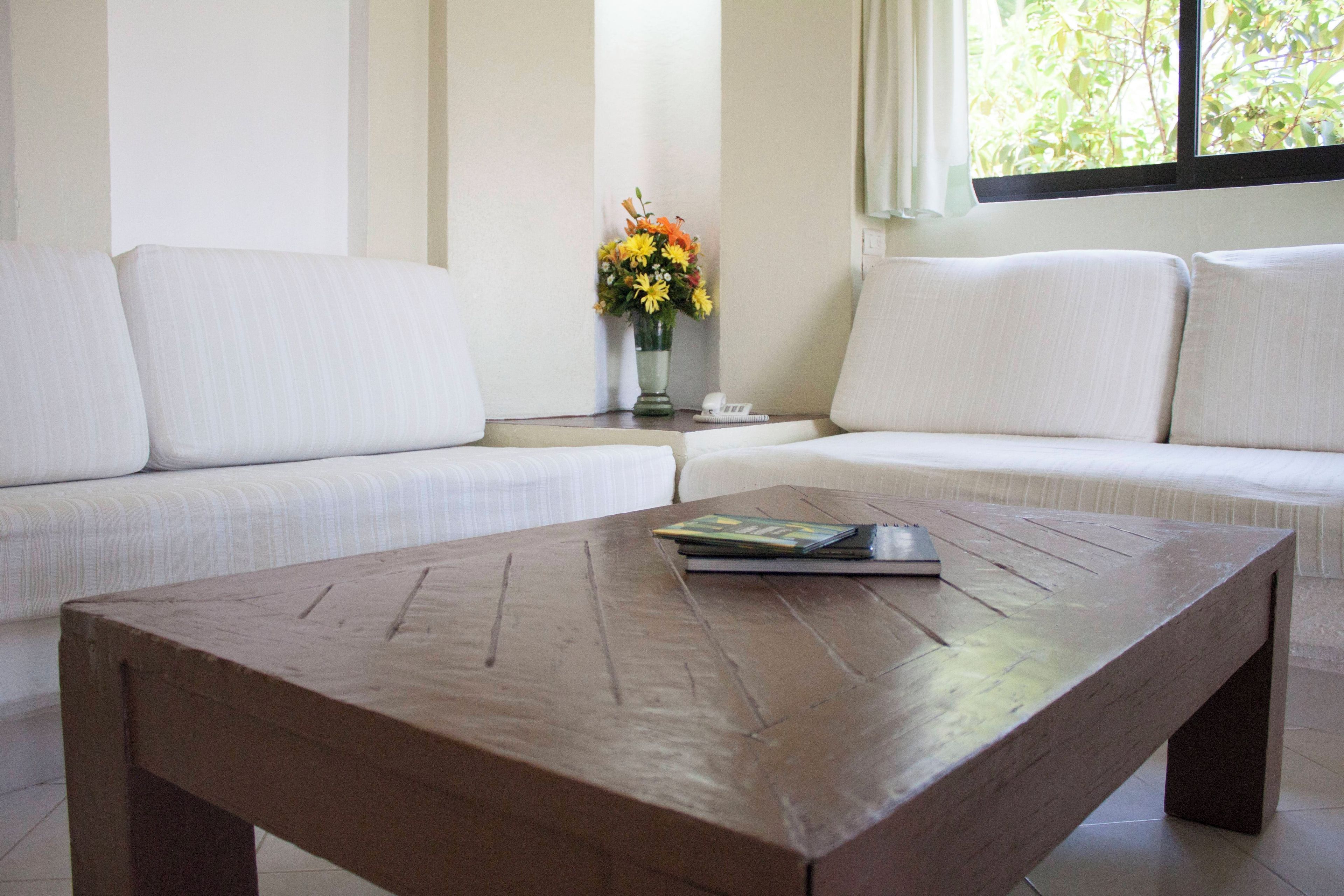 Una sala de estar con un sofá, una mesa de centro y un florero con flores.