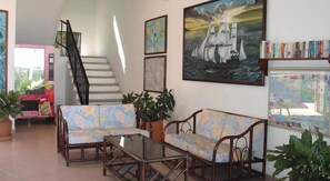 A spacious living area with a sofa, armchairs, a coffee table, and a staircase leading to an upper floor. - Coral Vista del Mar (Ixtapa)
