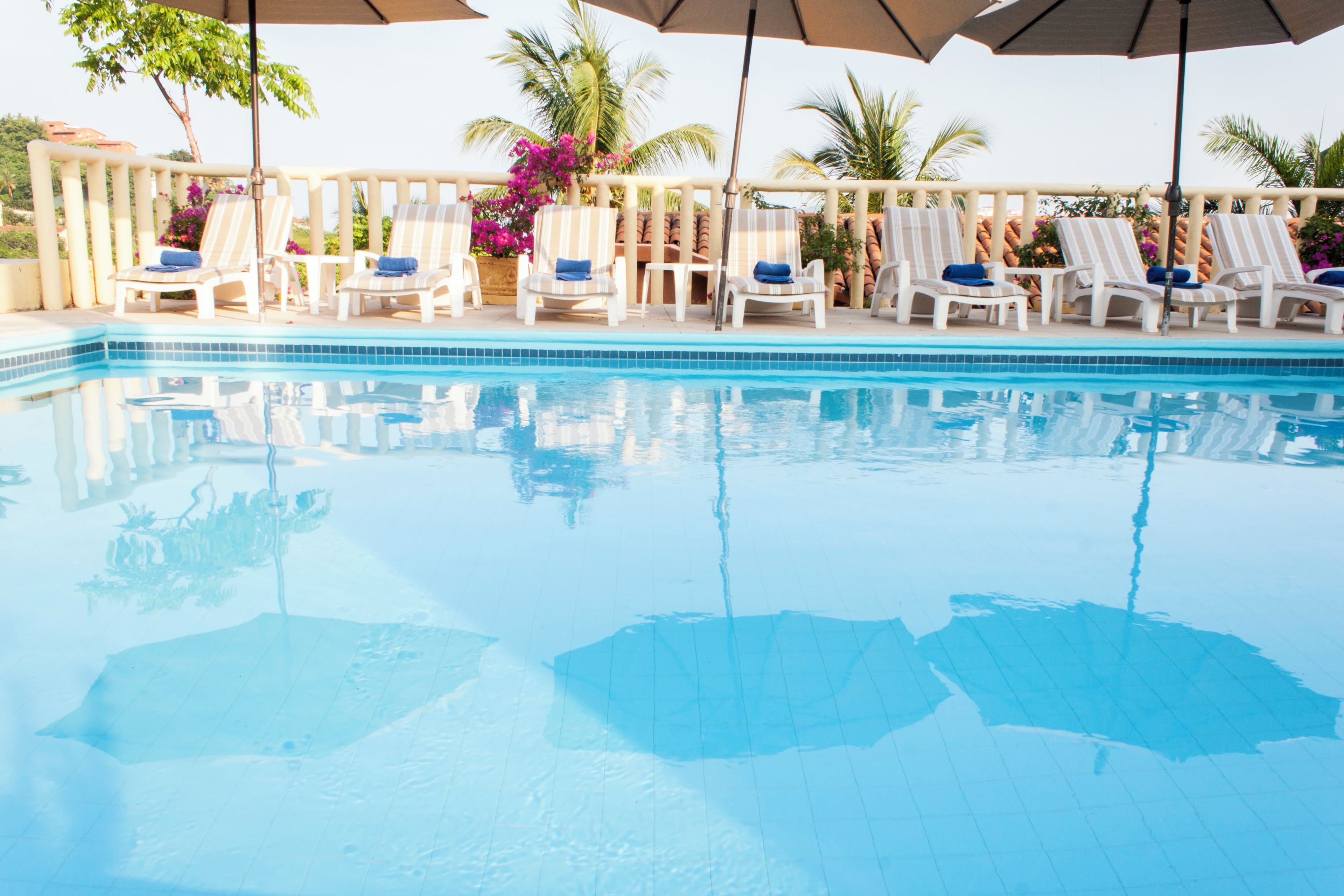 A swimming pool with lounge chairs and umbrellas.
