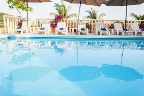 Une piscine avec des chaises longues et des parasols.