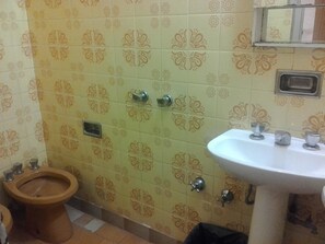 Et badeværelse med mønstrede fliser, toilet, håndvask og et spejl.