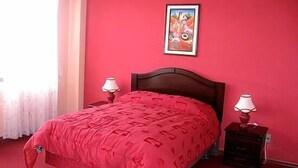 A room with a bed, two bedside tables, a window with curtains, and a painting on the wall. - Hotel Ensueños (La Paz)