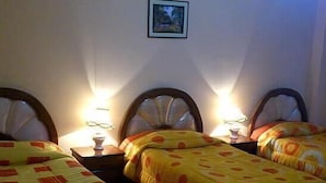 A room with three single beds, each with a wooden headboard and a bedside table with a lamp. - Hotel Ensueños (La Paz)