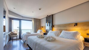 Ein modernes Hotelzimmer mit zwei Betten, einem Schreibtisch und Blick auf die Stadt.