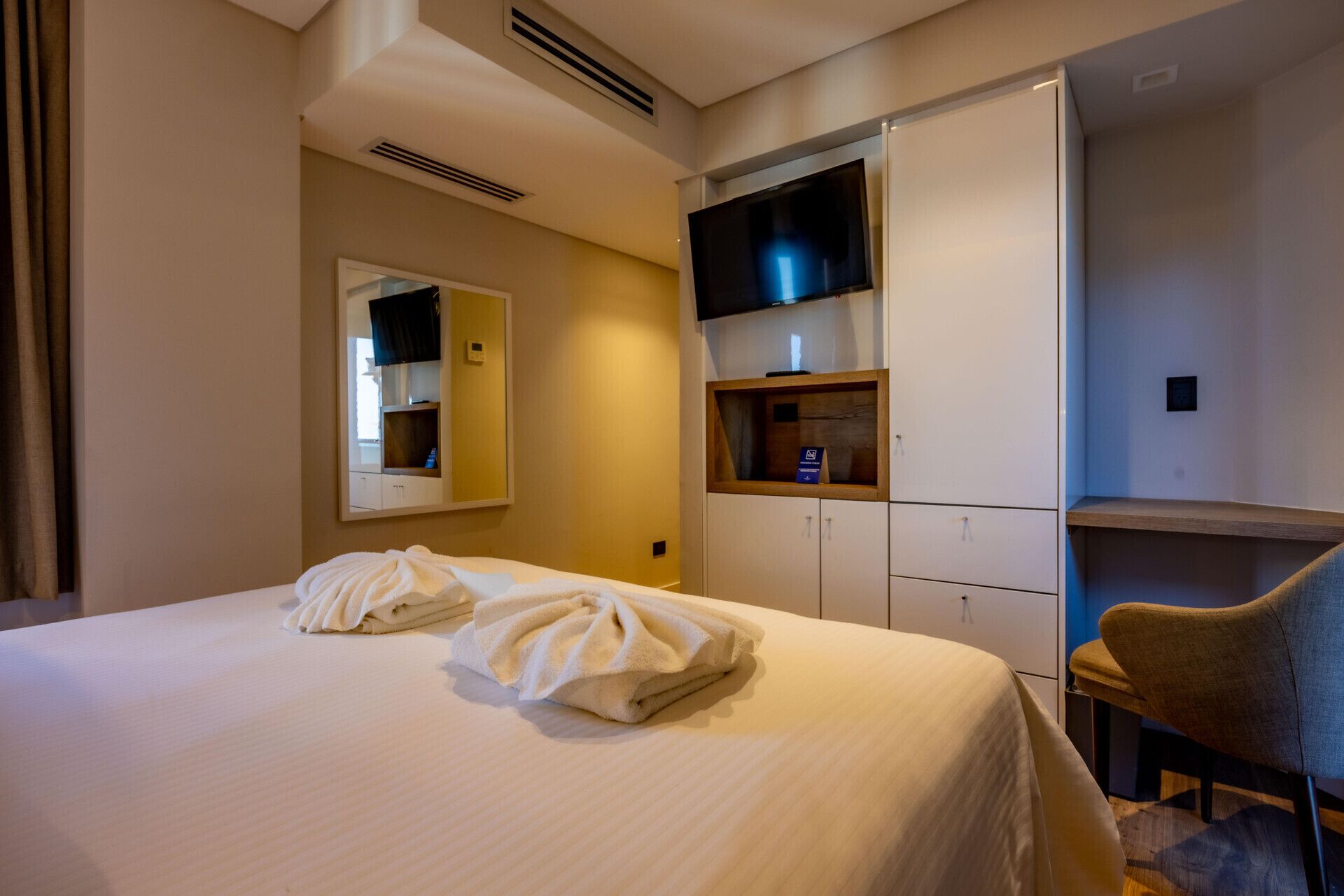 Una habitación de hotel con cama, televisión, escritorio y silla.