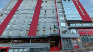 Un hotel con fachada moderna, varios pisos y una llamativa banda roja.