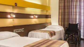 A hotel room with two beds, a wheelchair, and a curtain.