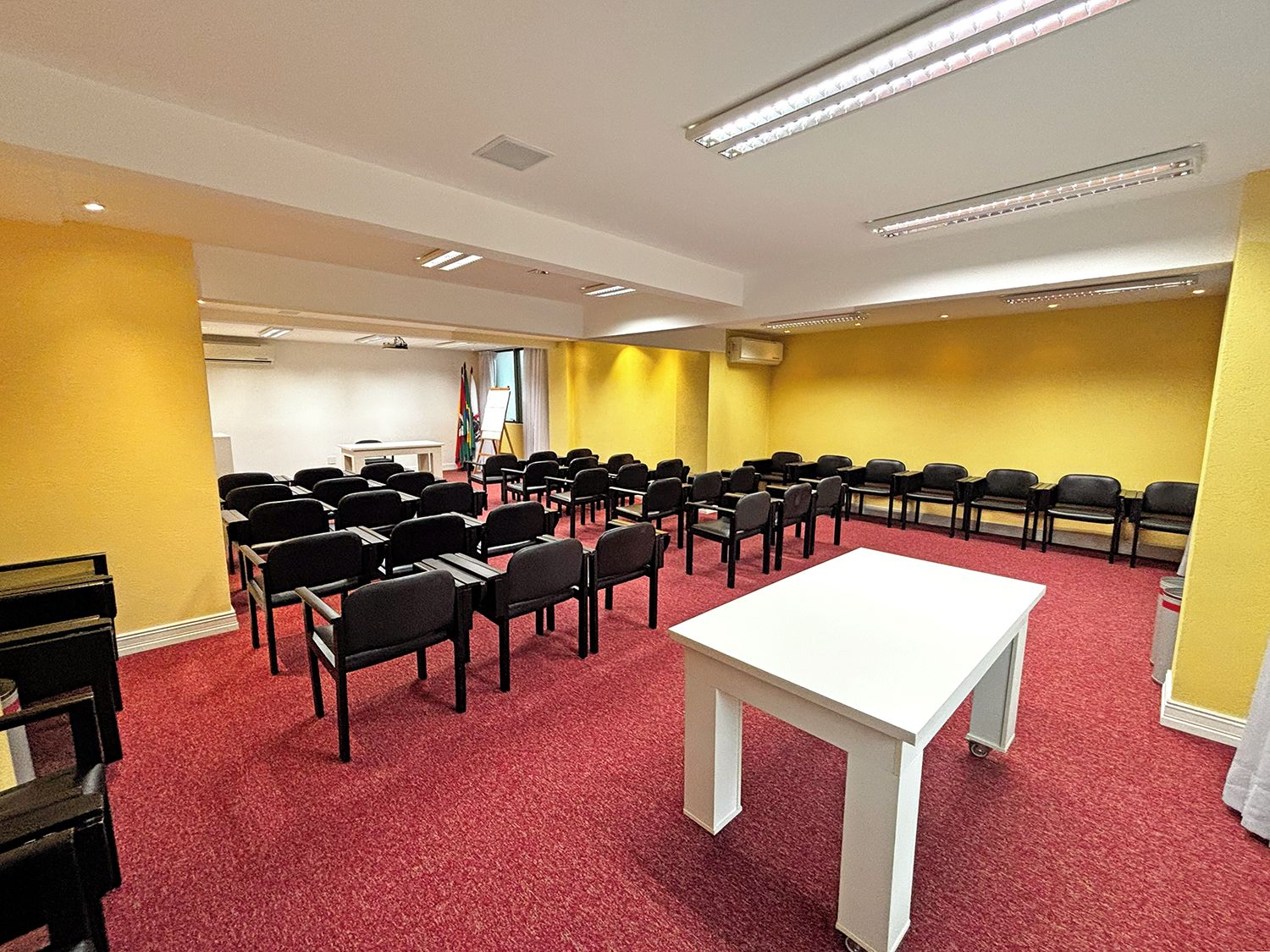 A conference room with rows of chairs, a white table, and a projector screen.