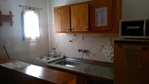 A kitchen with wooden cabinets, a gas stove, a sink, and a microwave.