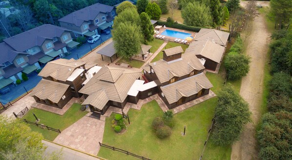 Eine Gruppe von Blockhütten mit Schwimmbad und gepflasterter Auffahrt.