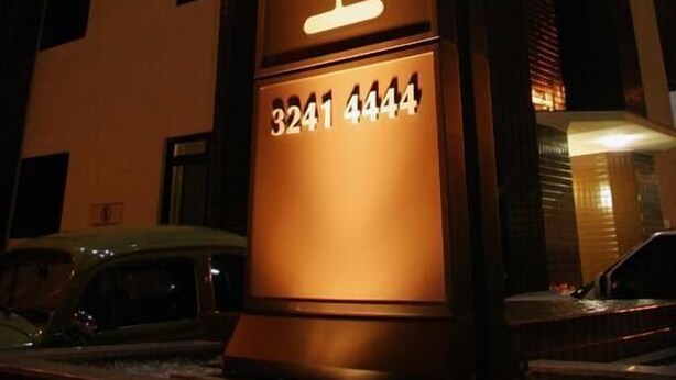 Letrero de hotel con el nombre 'HOTEL LINES' y el número '3241 4444' iluminado durante la noche.
