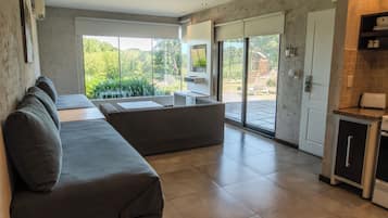 Una sala de estar moderna con un sofá, una mesa de comedor y una zona de cocina con refrigerador.