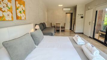 A hotel room with a bed, a desk, and a chair. There are two paintings on the wall.