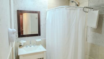 Casa de banho com lavatório branco, espelho, cortina de chuveiro e porta-toalhas.