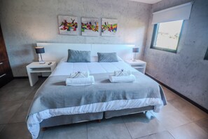 A modern bedroom with a large bed, two bedside tables, and a window.