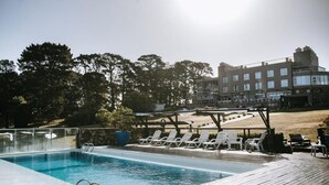Piscina com espreguiçadeiras e deck de madeira.