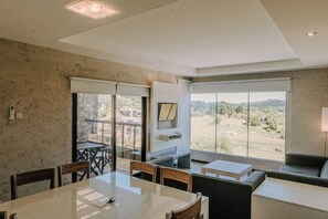 Habitació moderna amb zona de menjador, sofà i gran finestra amb vistes al camp.