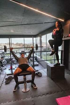 A gym with exercise equipment, large windows, and a view of the outdoors. - Apart & Hotel Posta Natural (Tandil)