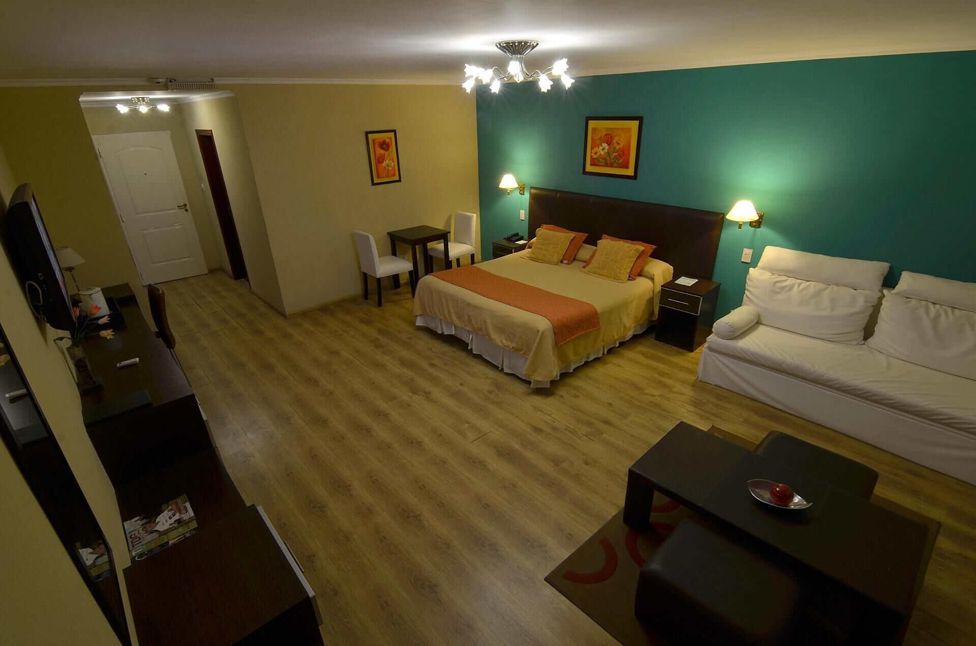Habitación de hotel con cama, escritorio, silla, sofá y televisor.