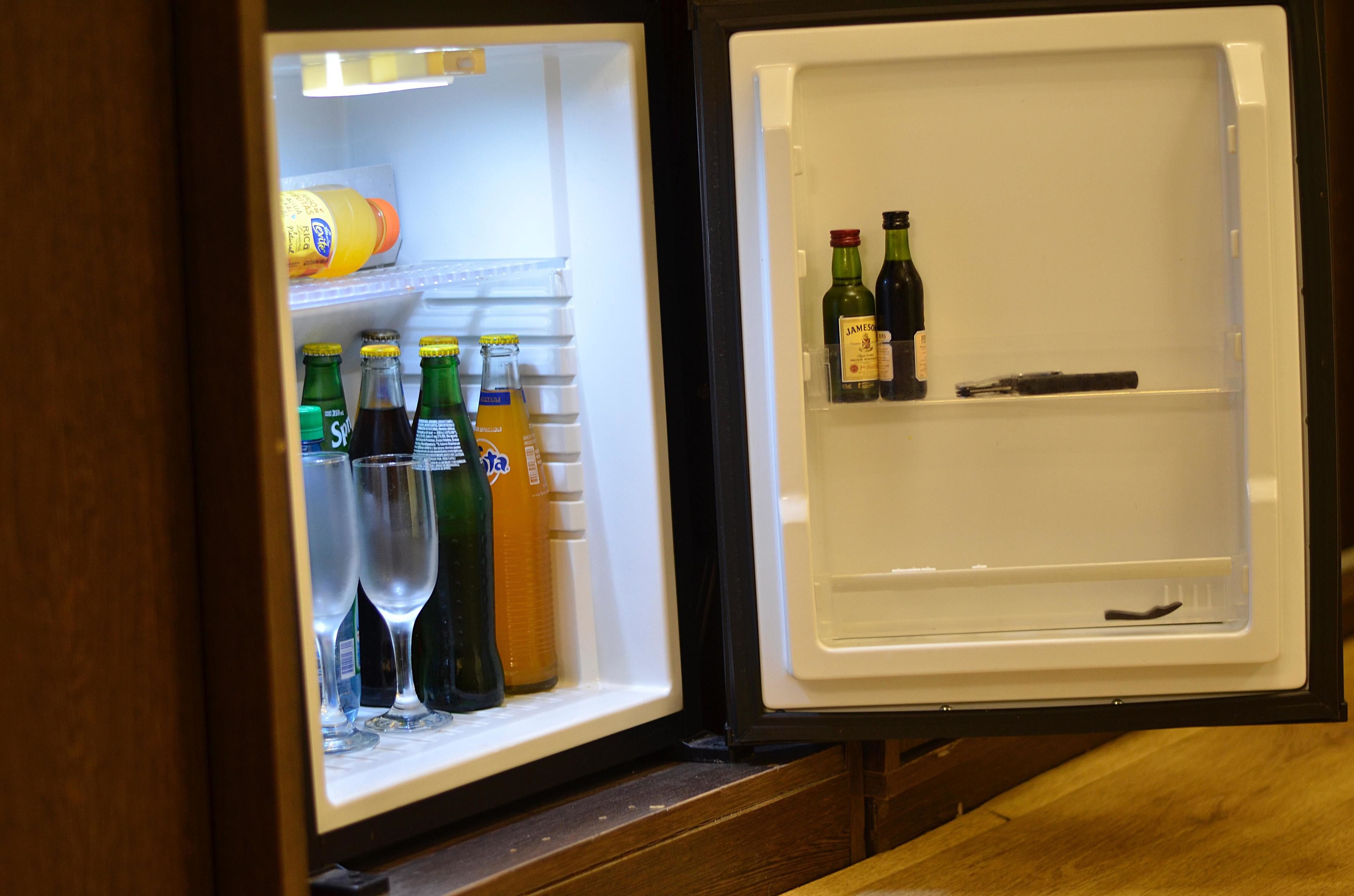 A refrigerator with shelves containing bottles and glasses.