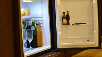 A refrigerator with shelves containing bottles and glasses.