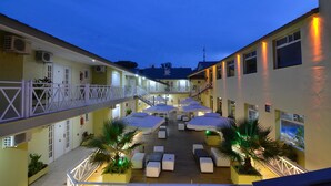 A hotel courtyard with outdoor seating, umbrellas, and a staircase connecting floors. - Alto Verde Suites and Apart (Termas de Rio Hondo)