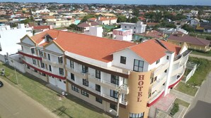 A multi-story hotel with a red-tiled roof, multiple balconies, and a prominent "HOTEL" sign. - Nelson Praia Hotel (Rio Grande)