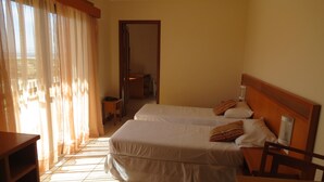 A hotel room with two beds, a wooden headboard, a table, and a chair. - Nelson Praia Hotel (Rio Grande)